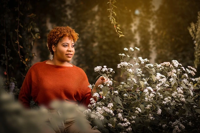 Zwarte vrouw naast bloemenstruik